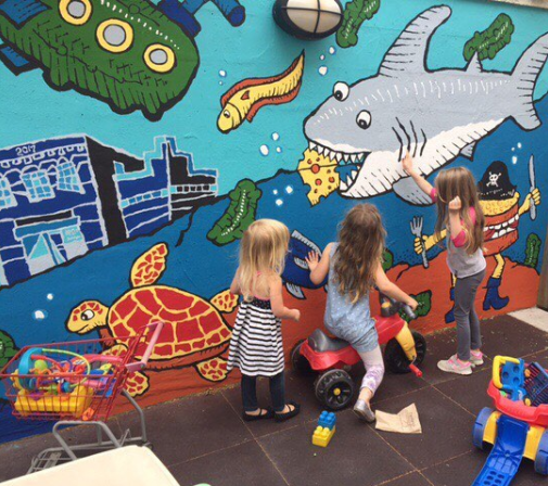 Kiddos playing in Zingerman's Deli play area in front of an underwater mural