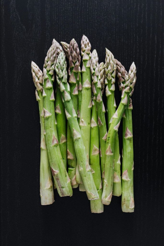 A bunch of asparagus spears on a black background.